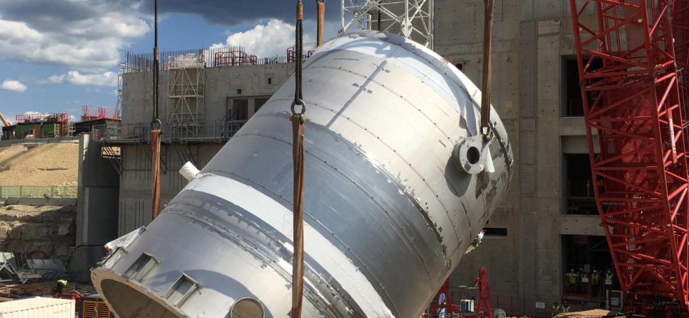 A 61,000 gallon drain tank, part of the US-provided tokamak cooling water system, is lifted into the tokamak complex for installation in the basement.